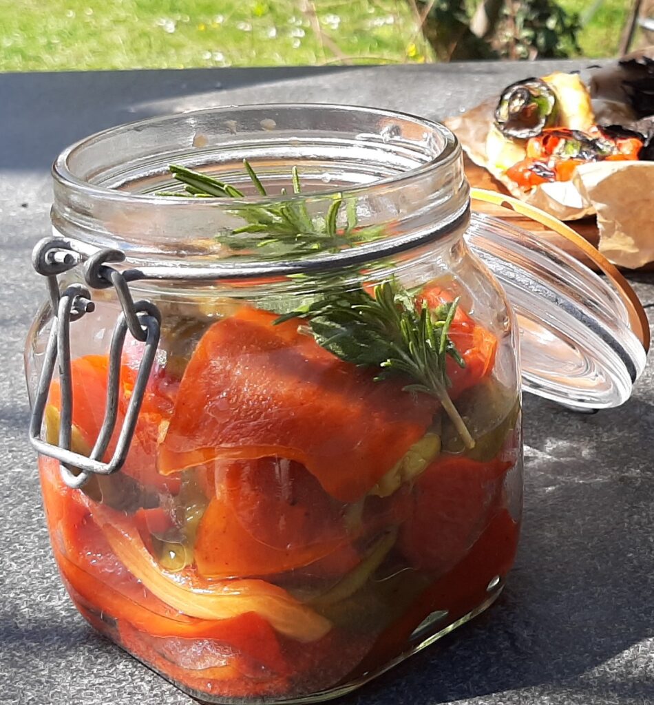 Red, yellow and green pepper grilled and combined in a transparent jar with olive oil, rosemary salt and pepper