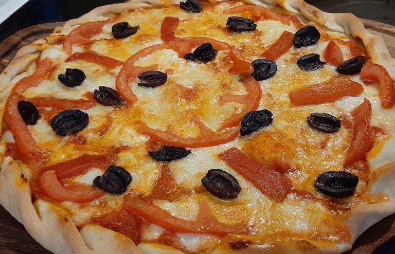 Pizza with black olives and red pepper on top