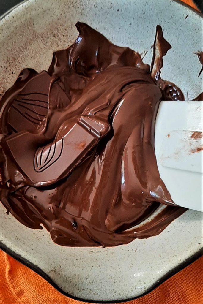 Blending melted dark chocolate in a light grey ceramic bowl