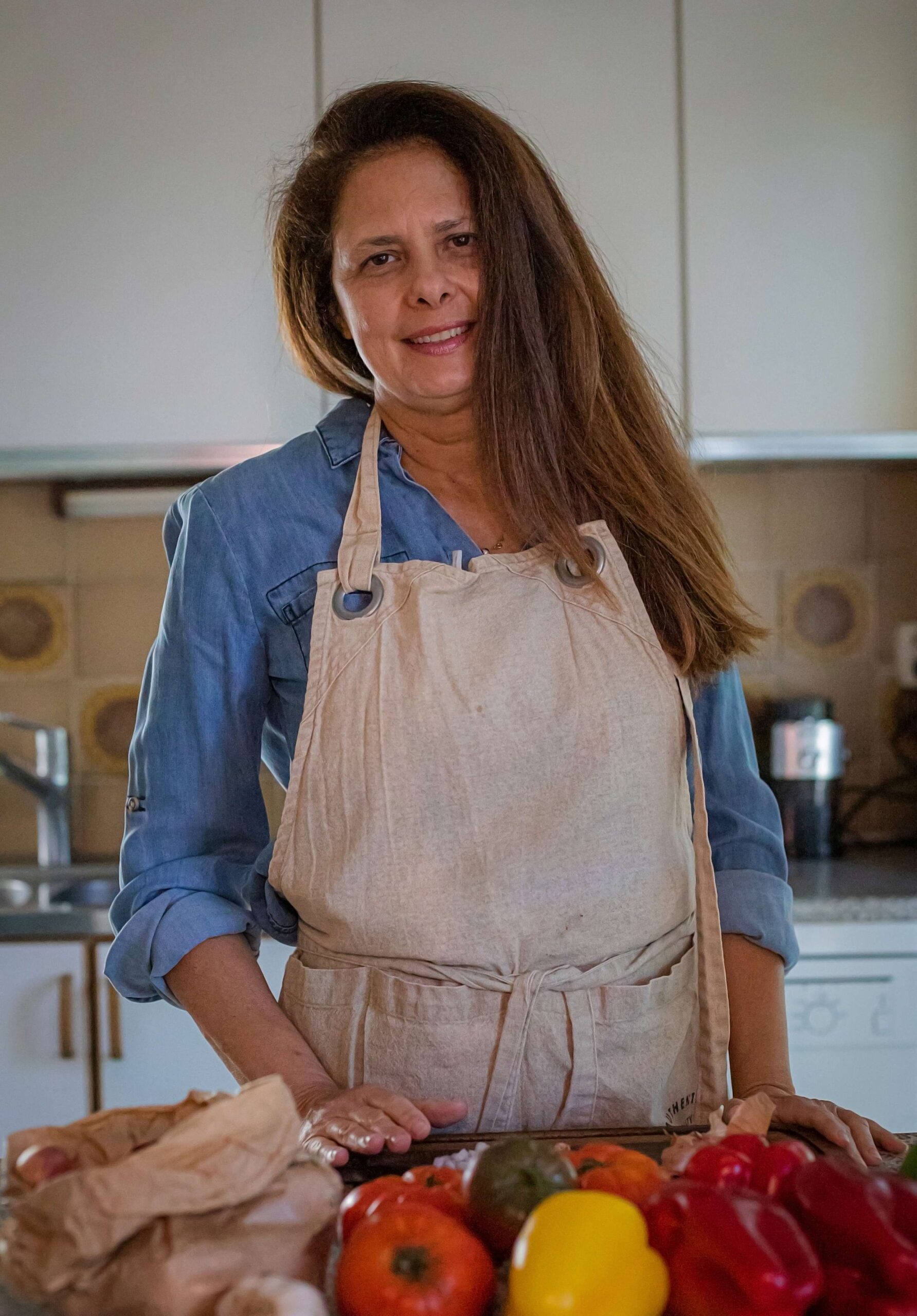 Creator of Home Cooking Academy standing up at her kitchen surrounded by vegetables about to de chopped